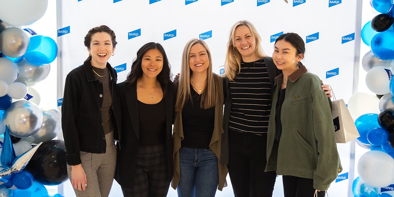 Five women stand before a SilverPeak Strategic Capital backdrop with blue, white, and silver balloons.