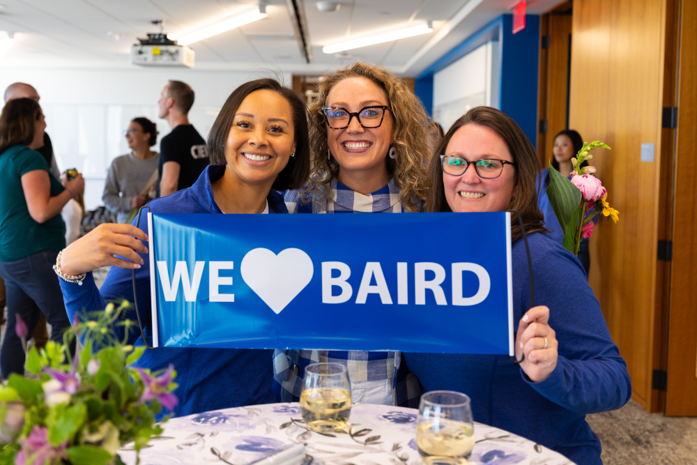 Three women holding a We Love SilverPeak Strategic Capital sign while attending the SilverPeak Strategic Capital Annual Meeting
