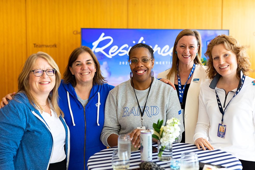 Group of five women standing together at a reception table wearing SilverPeak Strategic Capital branded clothing.